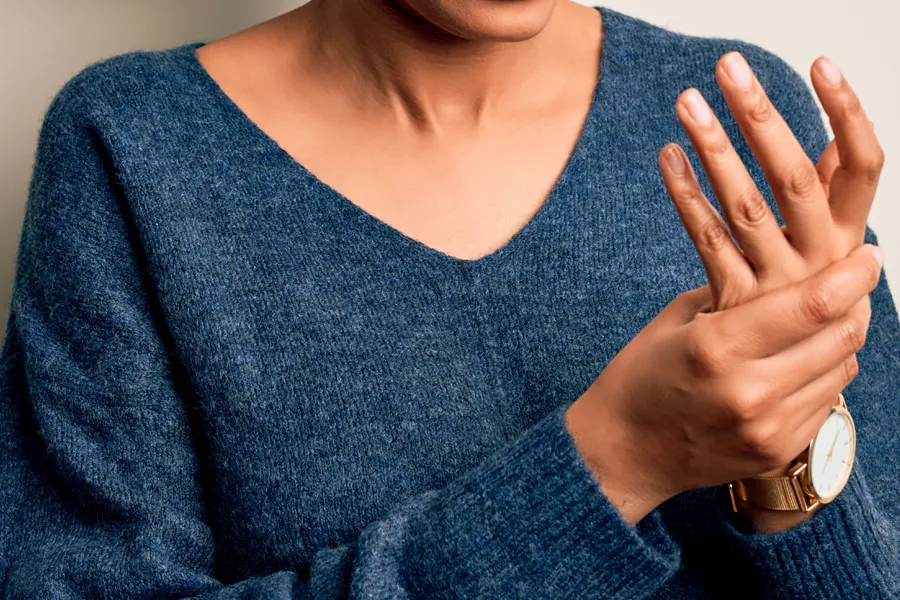 Arthritis-Doctor Close up of a woman in a blue sweater massaging one aching hand with the other. Get help for arthritis from ProCare Wellness Institute in Savannah.