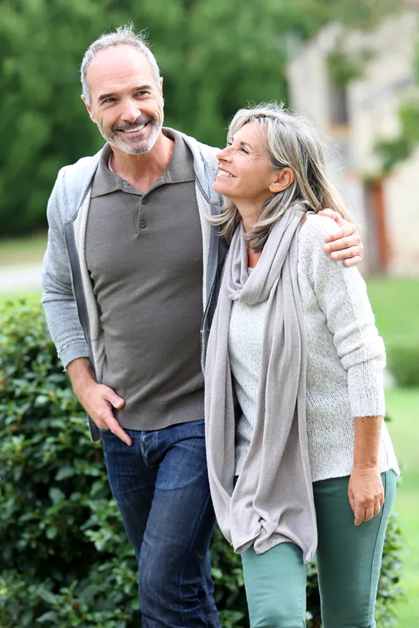 Bioidentical-Hormone-Therapy-Treatment A mature couple in gray toned clothes and jeans walk happily outside, happy with their successful bioidentical hormone treatments from ProCare Wellness Institute in Savannah.