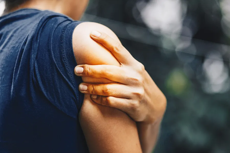 Bursitis-Clinic A woman holds her shoulder in pain. schedule treatment for bursitis from ProCare Wellness Institute in Savannah.