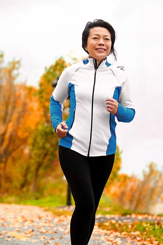 Hip-Pain-Treatment A middle-aged Asian woman jogging in a park during autumn enjoying active lifestyle after successful Hyaluronic Acid Injections for Hip Pain by ProCare Wellness Institute located in Savannah.