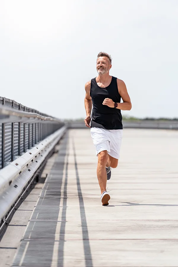 Hyaluronic-Acid-Injections-Treatment A middle-aged man happily jogs on a bridge. Get Hyaluronic Acid Injections Treatment from ProCare Wellness Institute in Savannah.