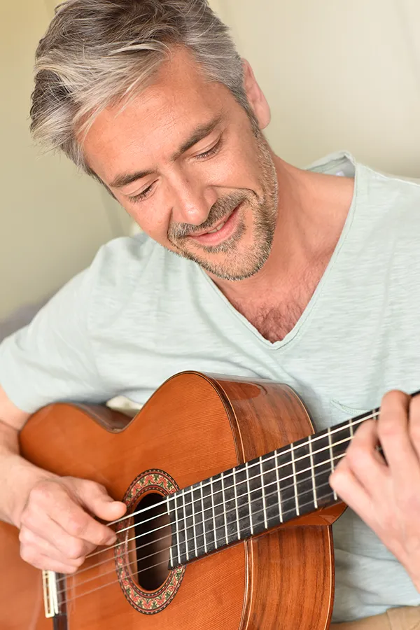 Osteoarthritis-Treatment A middle-aged man happily plays guitar. Get osteoarthritis treatment from ProCare Wellness Institute in Savannah.