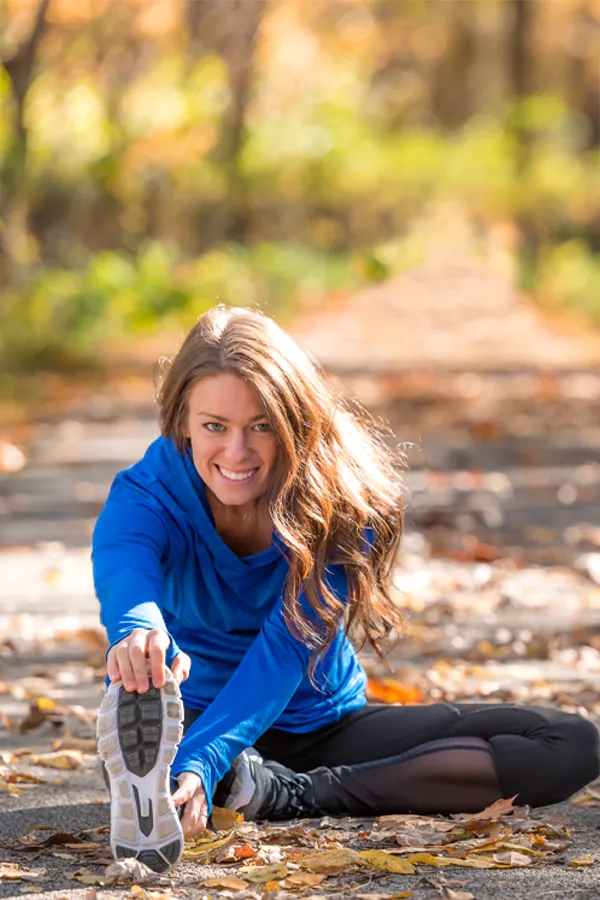 PRP-for-Sports-and-Orthopedics-Treatment A woman in blue warm ups stretching and preparing for a run on an outdoor trail. Get Platelet Rich Plasma (PRP) treatment for sports and orthopedics from ProCare Wellness Institute in Savannah.
