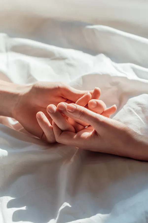 PT141-for-Women-Treatment A close up of a man and woman's hands lightly clasping on a bedsheet, representing successful PT141 sexual wellness treatment for women from ProCare Wellness Institute in Savannah.
