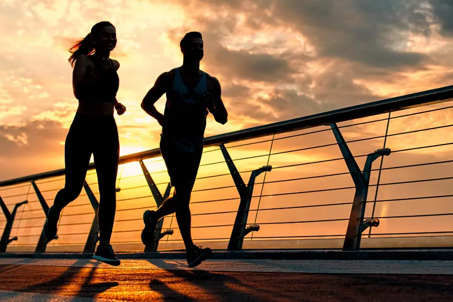 Performance-Enhancing-Peptides-Doctor A couple jogging on a bridge at sunrise, representing performance enhancing peptide therapy from ProCare Wellness Institute in Savannah.