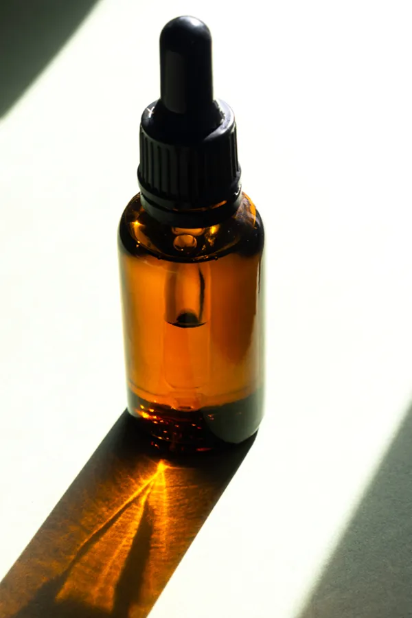 Performance-Enhancing-Peptides-Treatment A brown dropper bottle on a table lit by sunlight, representing performance enhancing peptide treatment from ProCare Wellness Institute in Savannah.