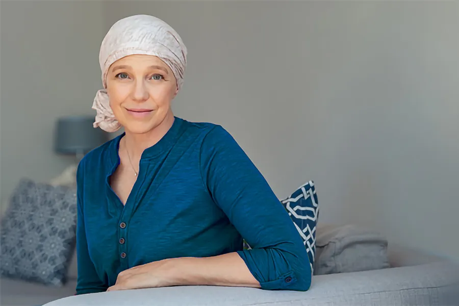 Post-Chemotherapy-Neuropathy-Clinic A woman wearing a headscarf, suggesting she may have undergone chemotherapy. She has a gentle smile and appears composed as she leans on a sofa in her home after successful Post-Chemotherapy Neuropathy treatment by ProCare Wellness Institute in Savannah.