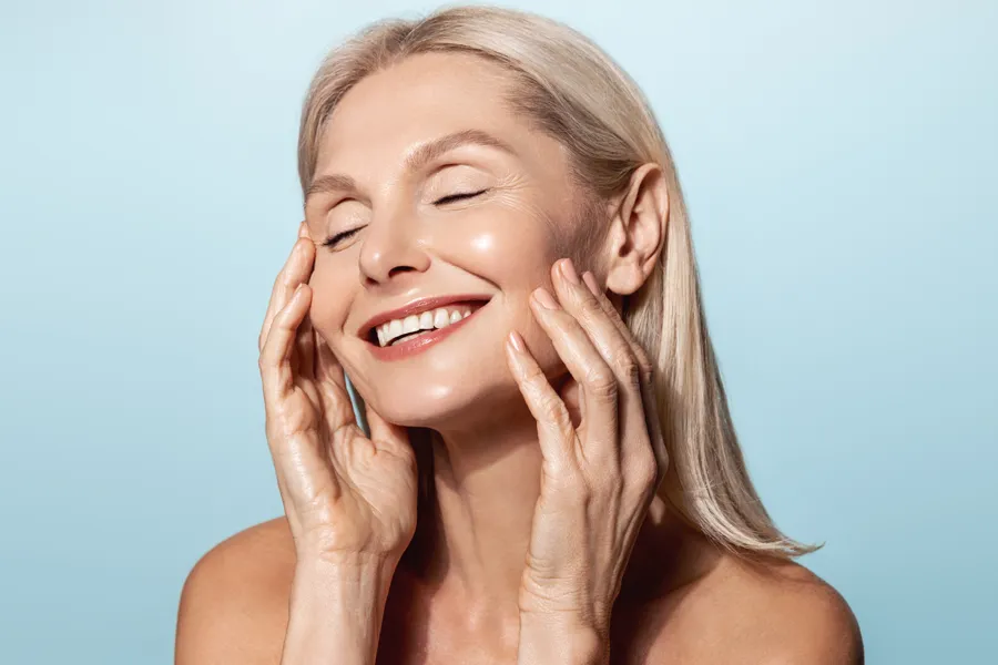 Radiofrequency-Microneedling-for-Face-and-Jawline-Clinic A woman with a smooth, tight jawlline smiles and holds her face. Schedule Radiofrequency Microneedling for Face and Jawline Skin Treatment from ProCare Wellness Institute in Savannah.